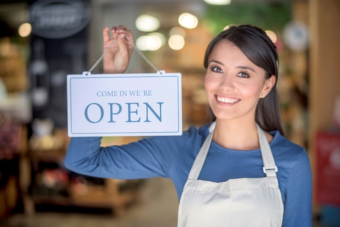 Woman holding an open sign at a grocery store